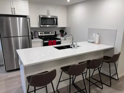 a kitchen with a sink and a refrigerator at The Lakefront - A new 2-bedroom in Mahogany Calgary in Calgary