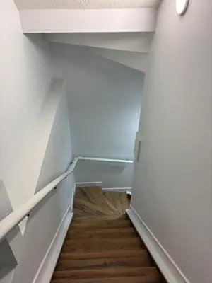 a staircase in a room with white walls and wooden floors at Home away from Home in Edmonton