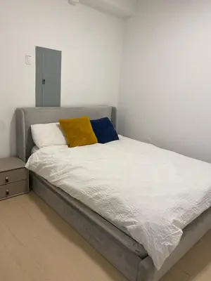 a bed with white sheets and a yellow pillow on it at Sunshine A in Vancouver