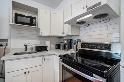 a kitchen with white cabinets and a black stove top oven at Private Guest Suite with Kitchen in Vancouver