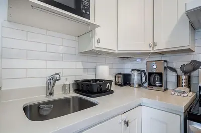 a kitchen with a stainless steel sink and white cabinets at Private Guest Suite with Kitchen in Vancouver