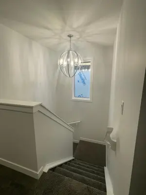 a staircase with a chandelier in a white room at Exquisite 4BR & 3 Baths 2000sqft Home in Calgary