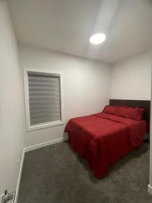 a bedroom with a red bed and a window at Exquisite 4BR & 3 Baths 2000sqft Home in Calgary