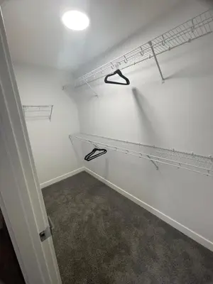 a walk in closet with white walls and shelves at Exquisite 4BR & 3 Baths 2000sqft Home in Calgary