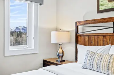 a bed with a lamp on a nightstand next to a window at Mountain View Penthouse 3BR with Private Hot Tub in Canmore