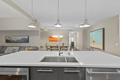 a kitchen with a sink and a living room at LUXUS 4BR Penthouse 2500sqft with Private Hot Tub in Canmore