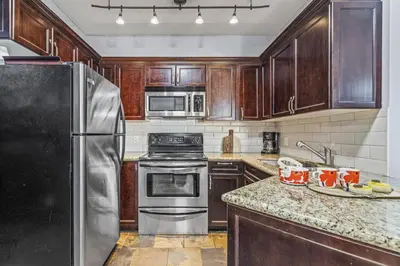 a kitchen with wooden cabinets and a stainless steel refrigerator at Perfect Rockies Escape with Pool, Hot Tub and Gym in Canmore