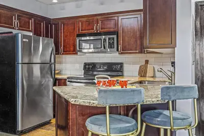 a kitchen with a stainless steel refrigerator and two bar stools at Perfect Rockies Escape with Pool, Hot Tub and Gym in Canmore