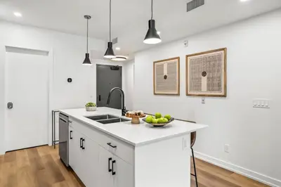 a white kitchen with a sink and a bowl of fruit on a counter at Brand New 1BR Canmore Retreat Hot Tub, Sauna, Gym in Canmore