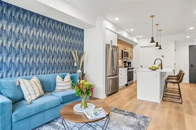 a living room with a blue couch and a kitchen at Brand New 1BR Canmore Retreat Hot Tub, Sauna, Gym in Canmore