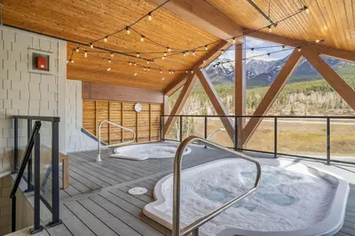 a hot tub in a room with a roof at Brand New 1BR Canmore Retreat Hot Tub, Sauna, Gym in Canmore