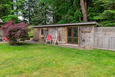 a wooden shed with two red chairs in a yard at The Wood Shed with hot tub in Oyster Bay