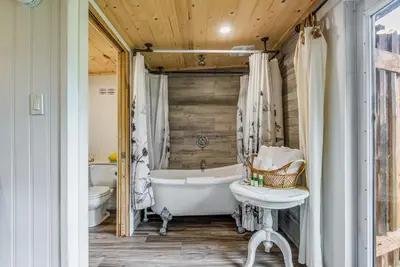 a bathroom with a tub and a toilet and a sink at The Wood Shed with hot tub in Oyster Bay