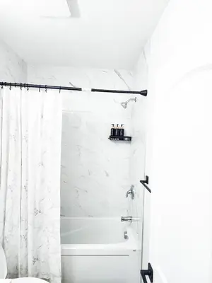 a white bathroom with a tub and a shower curtain at A true Home away from Home in Calgary