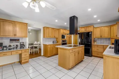a large kitchen with wooden cabinets and a large island at Acreage, 3 King Beds and Ensuites, Dance Floor, Fireplace, AC in Calgary