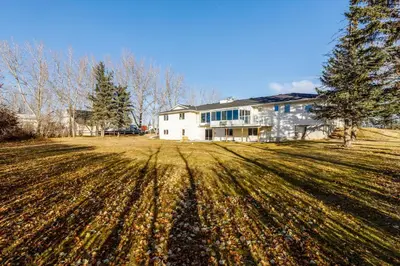 a large house with a large field of grass at Acreage, 3 King Beds and Ensuites, Dance Floor, Fireplace, AC in Calgary