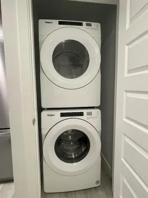 a washer and dryer in a small laundry room at Cozy and modern two bedroom guest suite in Calgary