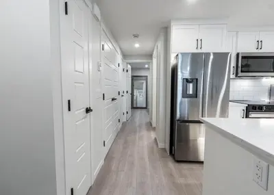 a kitchen with white cabinets and a stainless steel refrigerator at YYC Retreat - Near Mountains & Airport in Calgary