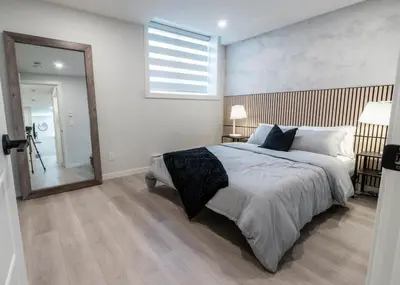 a bedroom with a large bed and a large mirror at YYC Retreat - Near Mountains & Airport in Calgary