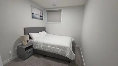 a white bedroom with a bed and a window at Modern 2BR Suite in Seton, Calgary in Calgary