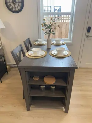 a dining room table with plates and chairs and a clock at Modern 1BR Suite with Laundry, Workspace & WiFi in Langford