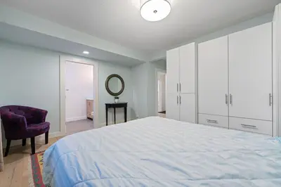 a bedroom with a bed and a chair and a mirror at Renovated North Vancouver Gem in North Vancouver