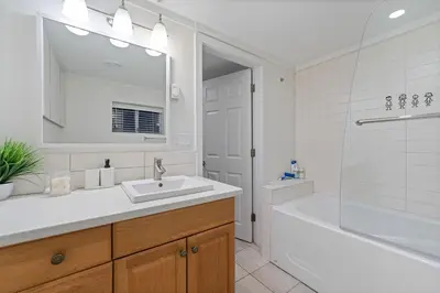 a white bathroom with a sink and a tub and a mirror at Renovated North Vancouver Gem in North Vancouver
