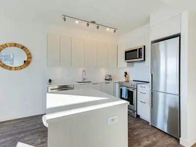 a kitchen with white cabinets and a stainless steel refrigerator at Corporate Stays Hazel 1 Bedroom in Burnaby