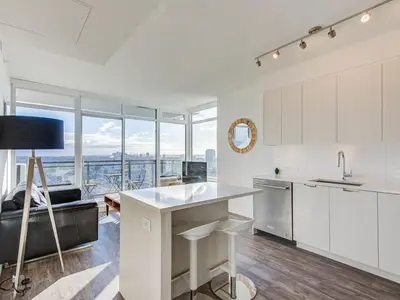a kitchen with white cabinets and a large window at Corporate Stays Hazel 1 Bedroom in Burnaby
