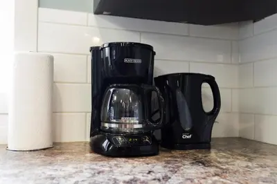 a black coffee maker sitting on a counter next to a roll of paper towels at 5BDRM Bright Modern Home-King Bed-Garage-Sleeps 12 in Edmonton