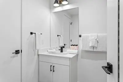 a white bathroom with a sink and a mirror at 3BR Mountain Bliss Retreat with Gym Hot Tub and Sauna in Canmore