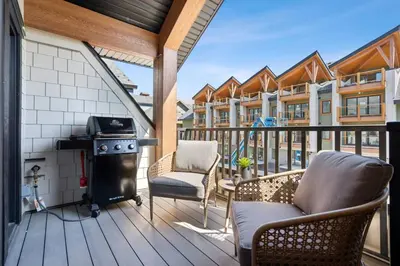 a patio with a stove and chairs on a deck at 4BR Golden Ridge Mountain Escape with Hot Tub and Gym in Canmore