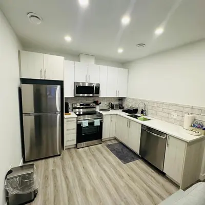 a kitchen with white cabinets and stainless steel appliances at Modern Basement Suite near West Edmonton Mall in Edmonton