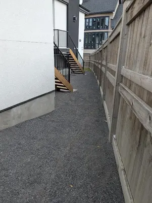 a fence next to a building with a sidewalk and stairs at 21 Greenwich Common NW Calgary Alberta in Calgary