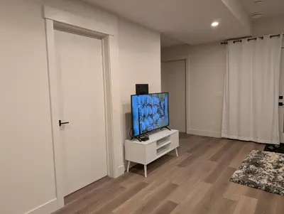 a living room with a flat screen tv on a cabinet at 21 Greenwich Common NW Calgary Alberta in Calgary