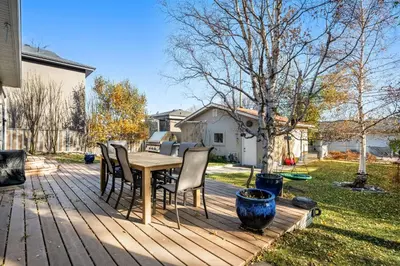 a wooden deck with a table and chairs on it at Family Friendly Welcoming Basement Suite in Calgary