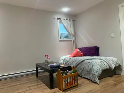a bedroom with a bed with a table and a window at A Cozy 2 beds Suite in Whistle Bend in Whitehorse