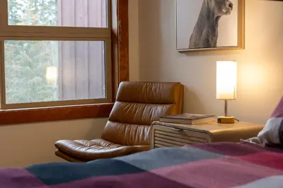 a bedroom with a bed and a chair and a window at Fully Renovated Penthouse Loft at Fernie Alpine Resort in Fernie
