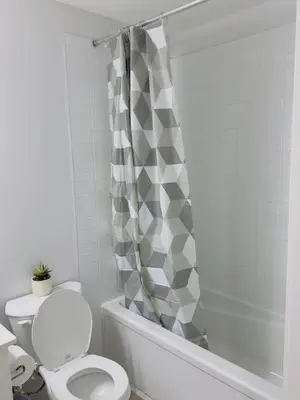 a bathroom with a toilet and a shower curtain at Modern Comfort West Edmonton in Edmonton