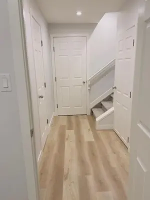 an empty hallway with white doors and wood floors at Modern Comfort West Edmonton in Edmonton
