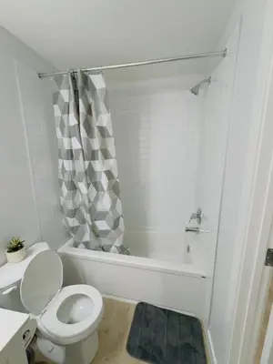 a white bathroom with a toilet and a bath tub at Modern Comfort West Edmonton in Edmonton