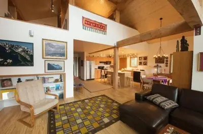 a living room with a leather couch and a dining room at Pemberton Tree Lodge in Pemberton