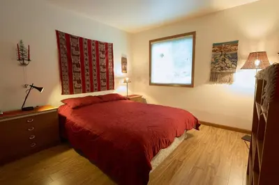 a bedroom with a red bed and a window at Pemberton Tree Lodge in Pemberton