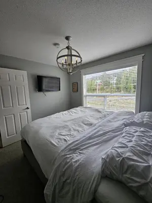 a bedroom with a bed and a window and a chandelier at White-Tail Hollow - 309 - 1105 Henry Rd in Courtenay