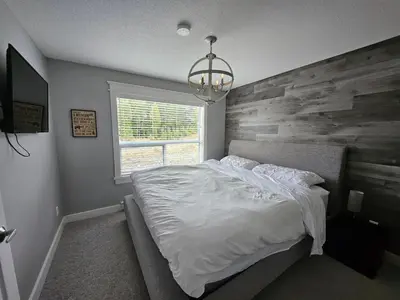 a bedroom with a bed with a wooden accent wall at White-Tail Hollow - 309 - 1105 Henry Rd in Courtenay