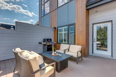 a patio with chairs and a table on a deck at Stunning Modern 2BR Unit in Downtown Canmore in Canmore