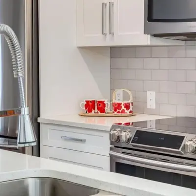 a kitchen with white cabinets and red cups on a counter at Stunning Modern 2BR Unit in Downtown Canmore in Canmore
