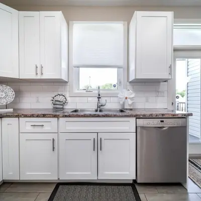 a kitchen with white cabinets and a stainless steel dishwasher at BoHo House-Sleeps 17-Garage-3 Kitchens-Fireplace in Edmonton