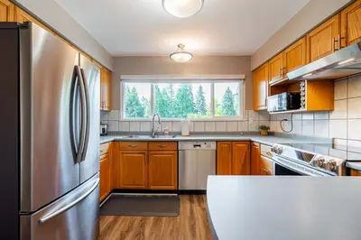 a kitchen with wooden cabinets and a stainless steel refrigerator at Serene Nature Retreat in North Vancouver