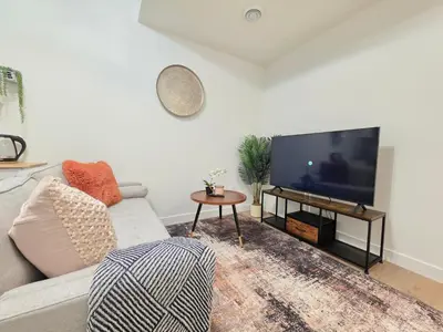 a living room with a couch and a flat screen tv at Amaville - One BRM Private Suite in West Edmonton in Edmonton